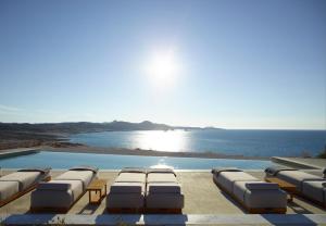 a swimming pool with lounge chairs and the ocean at Domes White Coast Milos, Adults Only - Small Luxury Hotels of the World in Mytakas