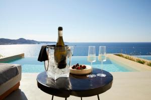 a table with a bottle of wine and two glasses at Domes White Coast Milos, Adults Only - Small Luxury Hotels of the World in Mytakas