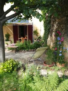 una silla en un jardín con flores y un árbol en Mas d'Antan, en Saint-Paul-les-Fonts