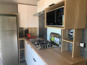 a kitchen with a microwave, refrigerator, sink and dishwasher at Location du Ranch in Algajola