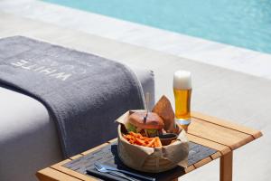 a table with a basket of food and a glass of beer at Domes White Coast Milos, Adults Only - Small Luxury Hotels of the World in Mytakas