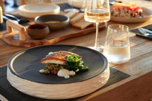 a plate of food on a table with wine glasses at Domes White Coast Milos, Adults Only - Small Luxury Hotels of the World in Mytakas