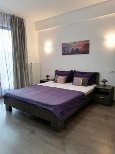 a bedroom with a large bed with purple sheets at Apartament Porto Del Mar in Mamaia Sat/Năvodari