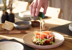 a person drizzling sauce onto a sandwich on a table at Domes White Coast Milos, Adults Only - Small Luxury Hotels of the World in Mytakas
