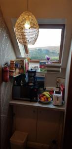 a kitchen counter with a bowl of fruit and a window at Tors Place in Portree