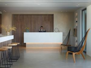 a person standing at a reception desk in a lobby at Domes White Coast Milos, Adults Only - Small Luxury Hotels of the World in Mytakas