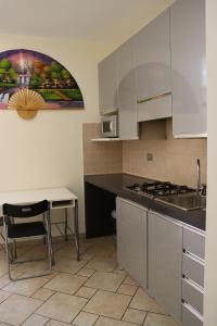 - une cuisine avec des placards blancs, une table et un évier dans l'établissement Studio Sole e Residenza Luna Assisi, à Assise
