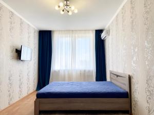 a bedroom with a blue bed and a window at Апартаменты В ЦЕНТРЕ ЖК "Шоколад" in Stavropol