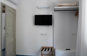 um quarto com uma televisão numa parede branca em Divina Holiday - Apartments em Maiori