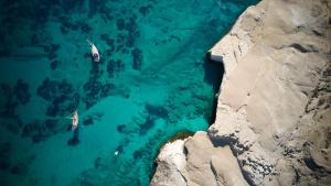 an aerial view of two boats in the water at Domes White Coast Milos, Adults Only - Small Luxury Hotels of the World in Mytakas