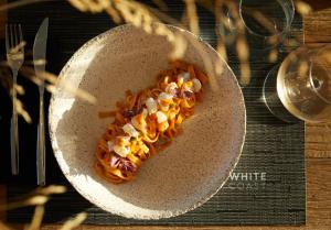 a white plate with food on a table at Domes White Coast Milos, Adults Only - Small Luxury Hotels of the World in Mytakas