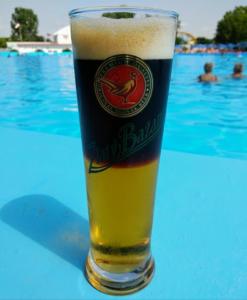a glass of beer sitting on a table next to a swimming pool at Ferienbungalow Tinka in Štúrovo