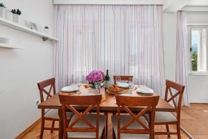 a dining room with a wooden table and chairs at Waikiki Beach House in Tivat