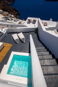 a swimming pool on top of a house with stairs at Santorini Delux in Imerovigli