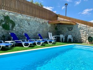 a pool with chairs and a table and a wall at Casa Varanda do Castelo in Ourém