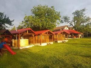 a row of wooden cabins with a red roof at Pensiunea Anisoara in Chişcău