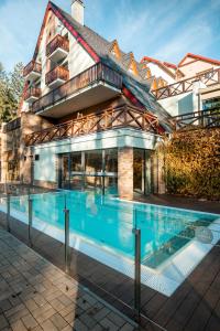 a house with a swimming pool in front of a building at Hotel Termál in Vyhne