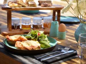 a plate of food on a table with a salad at Domes White Coast Milos, Adults Only - Small Luxury Hotels of the World in Mytakas