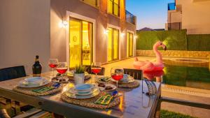 stół z kieliszkami wina i różowy łabędź na patio w obiekcie Atlantis - 4 Bedroom Holiday Villa in Hisaronu w Ölüdeniz