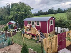 uma pequena casa vermelha num quintal com uma cerca em The Feathers Shepherds Hut em Áth Eascrach