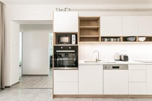 uma cozinha branca com armários e electrodomésticos brancos em Kaktusz City em Hévíz