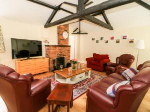 sala de estar con muebles de cuero y TV de pantalla plana en Claire Cottage, en Selby