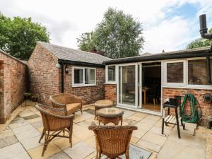 un patio avec des chaises en osier et une table dans l'établissement Claire Cottage, à Selby