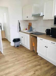 a kitchen with white cabinets and a wooden floor at Bright Apartment In The Center Of La Baule in La Baule