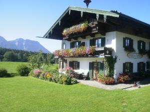 Une grande maison blanche avec des fleurs dans la cour dans l'établissement Gästehaus Restner - Chiemgau Karte, à Inzell