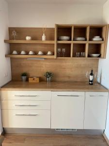 una cocina con armarios blancos y estanterías de madera en Apartment Araucaria, en Crikvenica