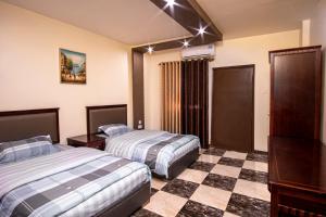 a hotel room with two beds and a checkered floor at Al Riyati Hotel Apartments in Aqaba