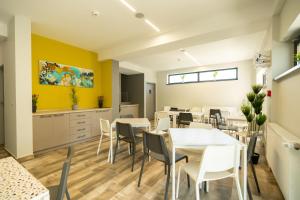 a restaurant with white tables and chairs and yellow walls at Onda Boutique Hotel in Mamaia Nord