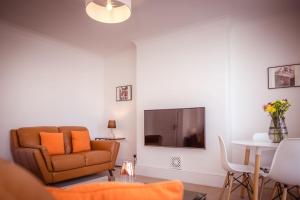 Little Chelsea Beacon - chic & central flat with parking في إيستبورن: غرفة معيشة بها أريكة وتلفزيون