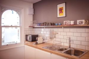 a kitchen with a sink and a microwave on a counter at Little Chelsea Beacon - chic & central flat with parking in Eastbourne