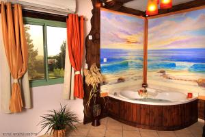 a bathroom with a bath tub with a painting on the wall at Spa of Nature in Ani'am