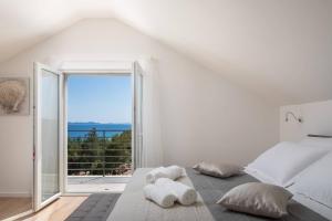 a white bedroom with a bed and a large window at WATERFRONT SEA DREAM VILLA in Milna