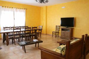 a living room with a dining table and a flat screen tv at Casa Rural Las Canteras in Trujillo