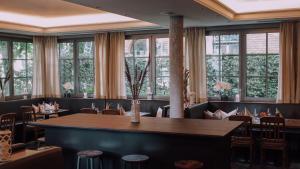 ein Esszimmer mit Tischen, Stühlen und Fenstern in der Unterkunft Restaurant & Hotel Engelkeller in Memmingen
