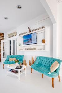 a living room with two blue couches and a tv at Boutique ''Di Mare'' Hotel & Suites in Posidhonía