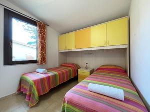 two beds in a room with yellow cabinets and a window at Erika in Castiadas