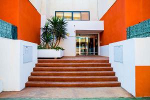 Un escalier mène à un bâtiment aux murs orange et blancs. dans l'établissement Apartamentos Adaria Vera, à Vera