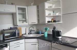 a kitchen with white cabinets and a sink and a microwave at Apartmenthaus am See - Seeblick Suite - Nähe Motorsportarena in Seehausen +10 photos
