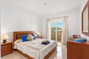 Un dormitorio con una cama con almohadas azules y una ventana en Villa Carvalho by Villa Plus, en Albufeira