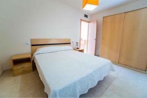 1 dormitorio con cama blanca y armario de madera en Apartamentos Adaria Vera, en Vera