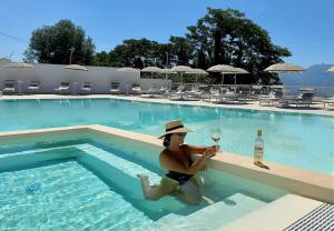Vesuvio Inn Bed & Wine Experience في Boscotrecase: امرأة جالسة في حمام سباحة مع كوب من النبيذ