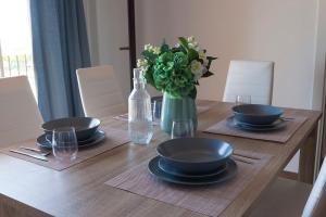 einem Holztisch mit Platten und einer Vase aus Blumen in der Unterkunft APARTAMENTO VIRGEN DEL CARMEN in Chipiona + 4 Fotos