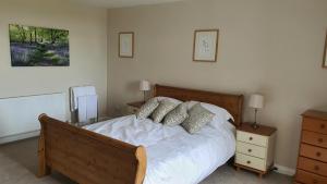una camera da letto con un letto con lenzuola e cuscini bianchi di Dairy Cottage with sea views a Girvan