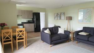 a living room with two chairs and a kitchen at Dairy Cottage with sea views in Girvan