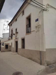 un edificio blanco con un balcón en el lateral. en Albergue Turístico "San Blas" de Oliva de Plasencia en Oliva de Plasencia