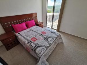 Un dormitorio con una cama con almohadas rosas y una ventana. en Casa Magnolia Queretaro TODO INCLUIDO, en Querétaro